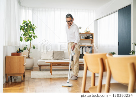 一名 50 多歲的中年男子正在家中吸塵 128393224