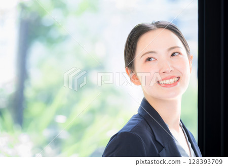Business scene of a woman in a suit holding a computer among beautiful soft fresh greenery, close-up, looking back Business scene of a woman in a suit holding a computer among beautiful soft fresh greenery, close-up, looking back 128393709