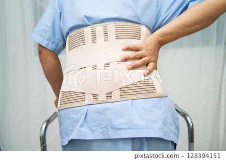 Asian senior pain back wearing elastic support belt with walker. 128394151