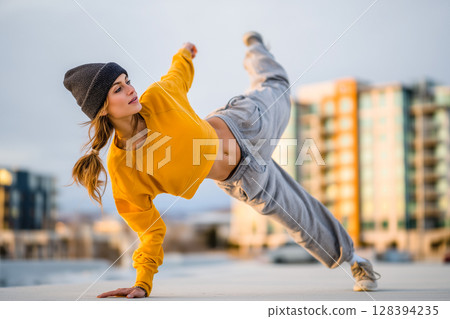 A woman in a yellow shirt is doing a handstand on a rooftop 128394235