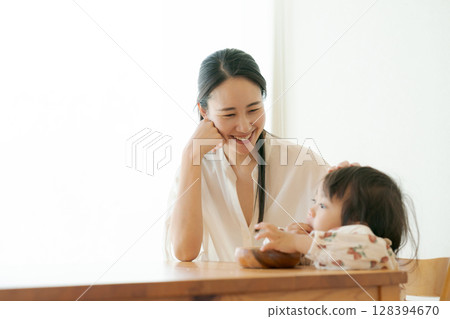 A mother watches over a child eating a snack 128394670