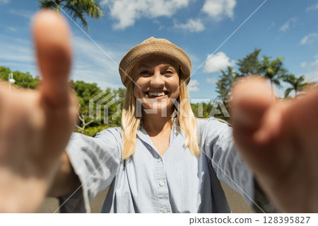 Woman with a bright smile invites you closer in a vibrant park 128395827