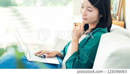 使用一台電腦在客廳裡的年輕女子 128396063