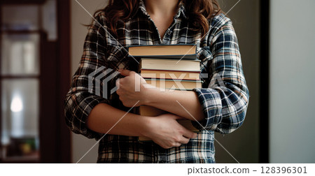 一位勤奮的女學生雙臂抱著一本書 128396301