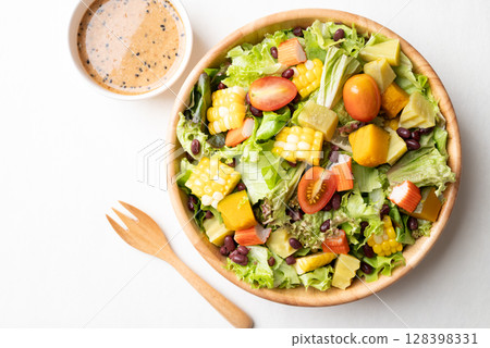 Top view of colorful vegetable salad in a rustic wooden bowl with Japanese sesame dressing  128398331