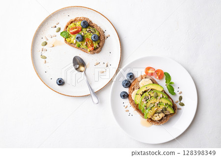 Avocado toast with banana, sunflower seeds, pumpkin seeds, sesame seeds, blueberry, tomato and honey 128398349