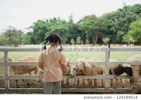 Child Feeding Sheep at Farm, Young Girl Enjoying Nature, Petting Animals, Close Connection with Farm Life, Outdoor Fun, Childhood Memories, Green Field Child Feeding Sheep at Farm, Young Girl Enjoying Nature, Petting Animals, Close Connection with Farm Life, Outdoor Fun, Childhood Memories, Green Field 128399018