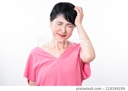 A senior woman with a wry smile, putting her hand on her head A senior woman with a wry smile, putting her hand on her head 128399289