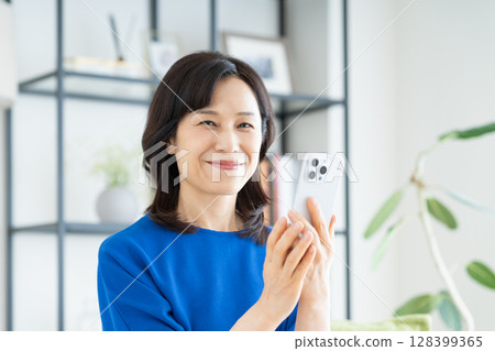 Middle-aged woman using a smartphone in the living room 128399365