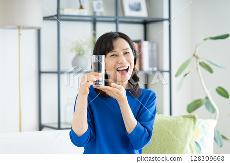 Middle aged woman drinking mineral water Middle aged woman drinking mineral water 128399668
