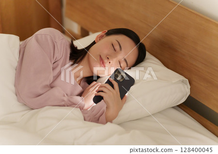 Woman using smartphone in bed at night Woman using smartphone in bed at night 128400045