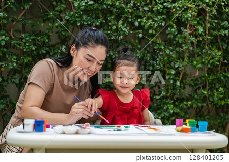 happy mother and toddler girl painting watercolor in paper at backyard. happy mother and toddler girl painting watercolor in paper at backyard. 128401205