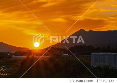 Beautiful countryside and the setting sun shining over the Aso mountain range (Miharashidai Station) (Minamiaso Village) 128402432