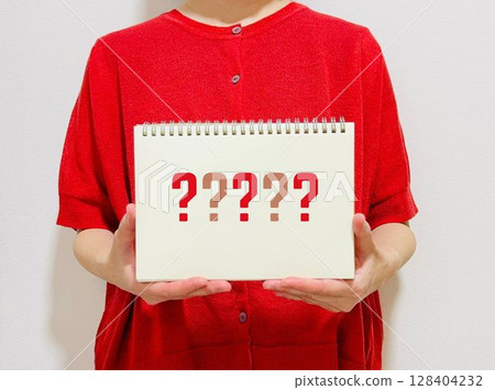 一位女士拿著一本帶有問號的筆記本 一位女士拿著一本帶有問號的筆記本 128404232