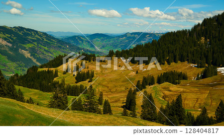 Breathtaking mountainous landscape filled with lush greenery and rolling hills under a bright blue sky Breathtaking mountainous landscape filled with lush greenery and rolling hills under a bright blue sky 128404817