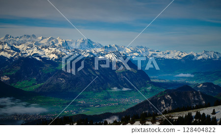 Majestic snow-capped mountains overlooking a lush valley in Switzerland during a clear day Majestic snow-capped mountains overlooking a lush valley in Switzerland during a clear day 128404822