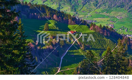 Scenic green hills with winding path and farmhouse in the Swiss countryside during daytime Scenic green hills with winding path and farmhouse in the Swiss countryside during daytime 128404848