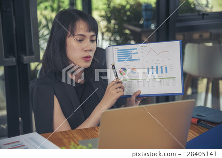 Business woman using smartphone, laptop on office desk. Female freelance reading financial graph charts Planning analyzing marketing data. Hands of young woman working in office firm business info. Business woman using smartphone, laptop on office desk. Female freelance reading financial graph charts Planning analyzing marketing data. Hands of young woman working in office firm business info. 128405141