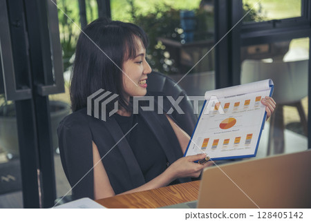 Asian businesswoman vdo call conference telecommunicate office desk. Women show Graph business report online meeting. Freelance women using laptop home office technology. Businesswoman online meeting Asian businesswoman vdo call conference telecommunicate office desk. Women show Graph business report online meeting. Freelance women using laptop home office technology. Businesswoman online meeting 128405142