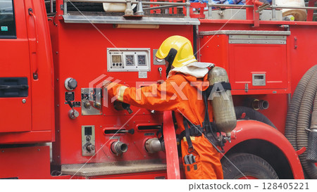Fireman prepare equipment at fire engine truck. Man hand connect water tube with fire truck fighting extinguisher. Firefighter using fire hose, tube, chemical water foam spray police rescue training Fireman prepare equipment at fire engine truck. Man hand connect water tube with fire truck fighting extinguisher. Firefighter using fire hose, tube, chemical water foam spray police rescue training 128405221