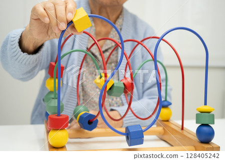 Asian elderly woman playing enhancing skill board game. Asian elderly woman playing enhancing skill board game. 128405242