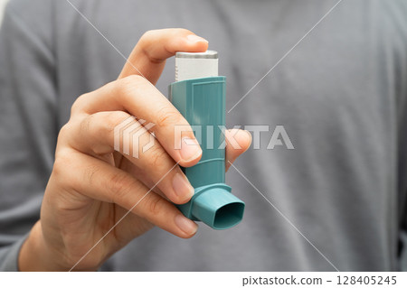 Asthma and chronic obstructive pulmonary disease COPD, Asian young man using metered dose inhaler MDI. Asthma and chronic obstructive pulmonary disease COPD, Asian young man using metered dose inhaler MDI. 128405245