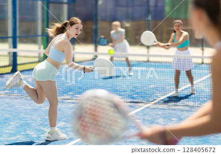 Woman playing with other paddle tennis players 128405672