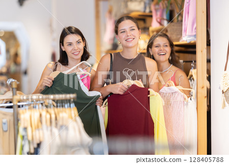 Three happy and laughing girls are shopping in clothing store 128405788