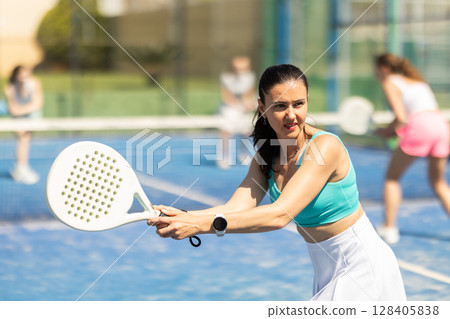 Woman on the court playing paddle tennis Woman on the court playing paddle tennis 128405838