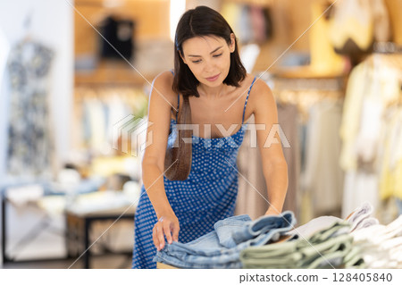 Adult woman choosing shorts in clothing store 128405840