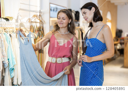 Women friends choose a dress together in a store 128405891