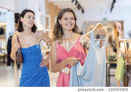 Two girls customer chooses dress in store 128405903