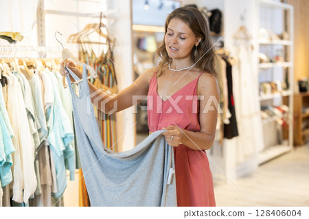 Girl customer chooses dress in store Girl customer chooses dress in store 128406004