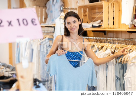 Young woman choosing clothes in a store in summer 128406047