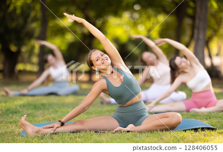Group of young women doing stretching in park 128406055