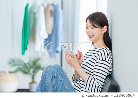 A young woman using a smartphone in the living room 128406064