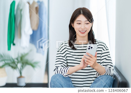 A young woman using a smartphone in the living room 128406067
