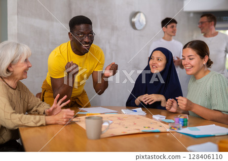 Cheerful african american man playing board game with friends Cheerful african american man playing board game with friends 128406110