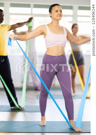 Group of athletes train in Pilates class using elastic bands Group of athletes train in Pilates class using elastic bands 128406144