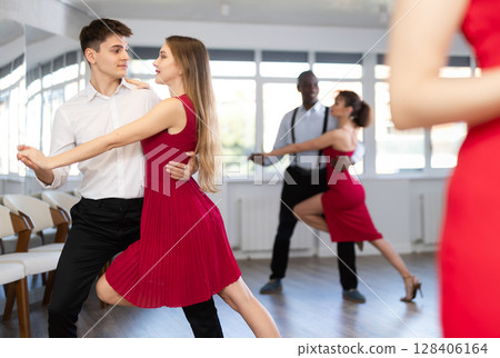Happy woman enjoying impassioned merengue with male partner in dance room during party. Social dancing concept Happy woman enjoying impassioned merengue with male partner in dance room during party. Social dancing concept 128406164