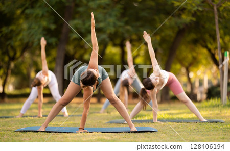 Yoga lesson visitors girls perform Himavanasana in park Yoga lesson visitors girls perform Himavanasana in park 128406194
