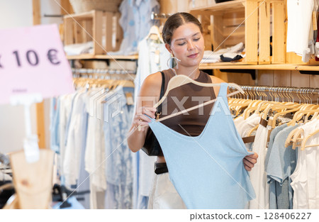 Happy woman buyer chooses evening blue dress in clothing store Happy woman buyer chooses evening blue dress in clothing store 128406227