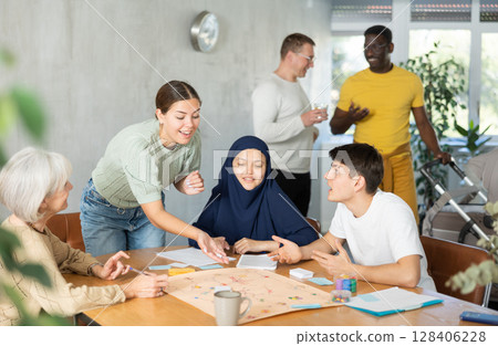 Group of multinational students of different years play board game with passion Group of multinational students of different years play board game with passion 128406228