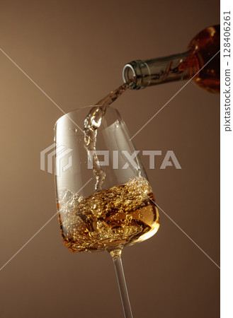 Pouring white wine from a bottle into a glass. 128406261