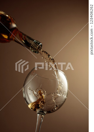 Pouring white wine from a bottle into a glass. 128406262