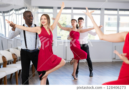 African American practicing bachata with brunette in red in dance class African American practicing bachata with brunette in red in dance class 128406273