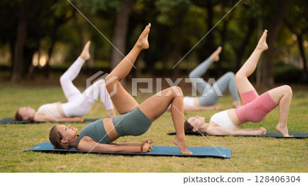 Group of young women doing yoga in park 128406304