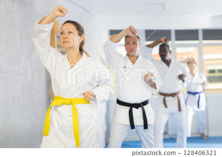 Multinational students repeat position and perform sequence of punches and painful techniques kata 128406321