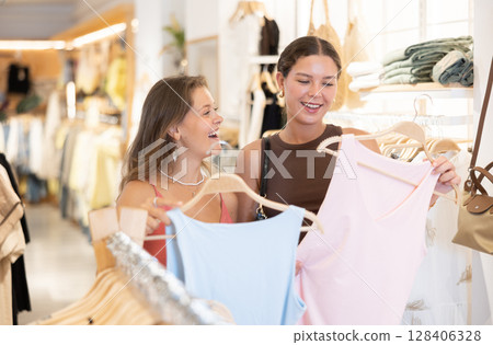 Two women are standing in a store and choosing tank top Two women are standing in a store and choosing tank top 128406328