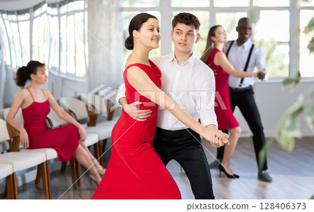 Man and Asian woman dancing waltz in couple during lesson at studio 128406373